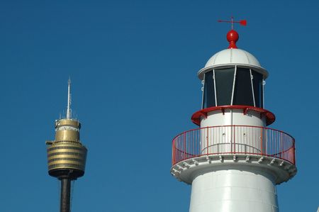 white lighthouse with red parts and sydney tower, blue sky, simple photoの写真素材