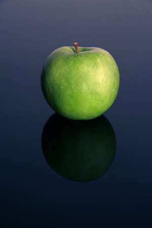 green isolated apple on blue reflective background,の写真素材