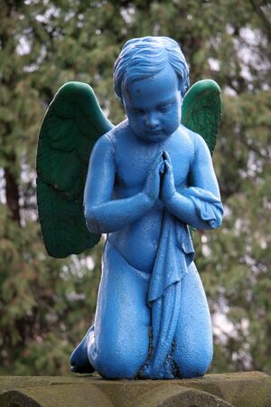 blue praying angel, blurred trees in background, photo taken in Presov, Slovakiaの写真素材