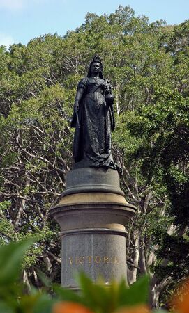 queen victoria sculpture in sydney; trees in background, flowers in foregroundの写真素材