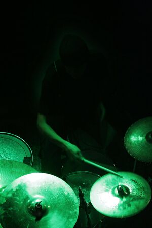 a man in shadow (not visible) is playing on drums, green lightの写真素材