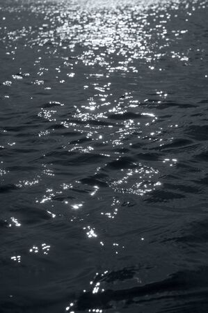 photo of sun reflections in a dark black water, photo taken against sun