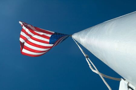 usa flag waving on a white pole, clear blue skyの写真素材