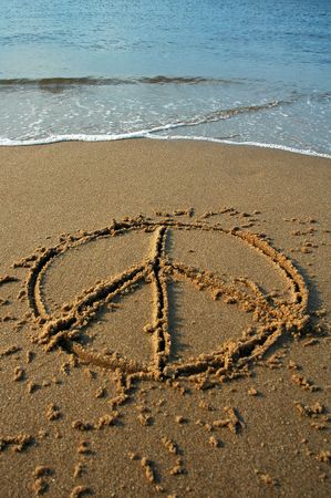 peace sign written in sand on a beach, cyan water in backgroundの写真素材