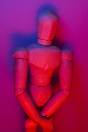 conceptual photo of a wooden figure, red and blue mixed lights, shy expressionの写真素材