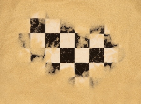 damaged checkered race flag buried in sandの写真素材