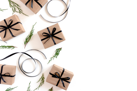 Border frame made of conifer tree branches, atlas ribbons, gift boxes packed in kraft paper on a white backgroundの写真素材
