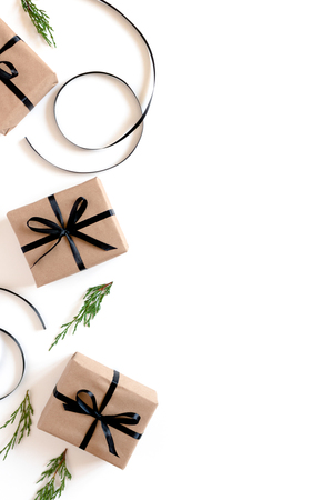 Border frame made of conifer tree branches, atlas ribbons, gift boxes packed in kraft paper on a white backgroundの写真素材
