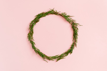Wreath made from conifer tree branches on a pink pastel backgroundの写真素材