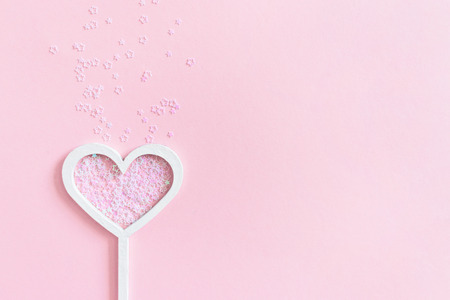 Heart shaped magic wand with star sequins on a pink pastel backgroundの写真素材