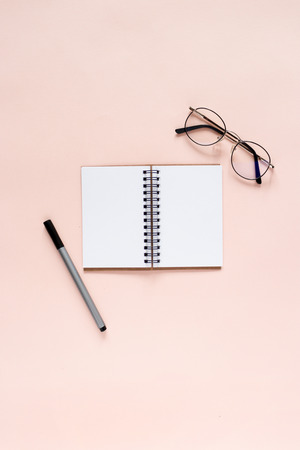 Minimal composition with open notepad, pen, glasses on a pink pastel backgroundの写真素材
