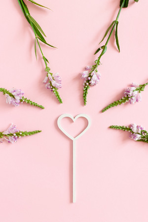 Valentine's Day composition with magic wand and wild flowers on a pink pastel backgroundの写真素材