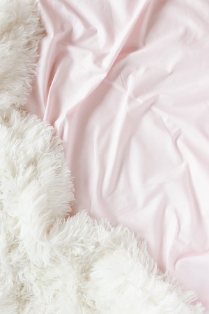 Pale pink linens and white fluffy blanketの写真素材