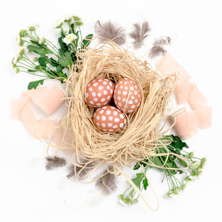 Easter composition with eggs, pink ribbons, feathers and chrysanthemum flowers on white backgroundの写真素材
