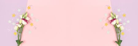 Eustoma flowers and stars confetti on a purple and pink pastel background. Banner with place for text.の写真素材
