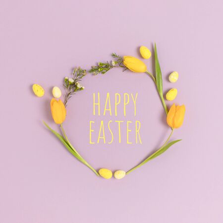 Wreath made of eggs and flowers on a purple pastel background. Quote Happy Easter. Holiday concept.の写真素材