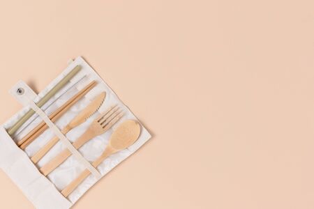 Set of bamboo cutlery in a case on a beige background. Zero waste concept with place for text.