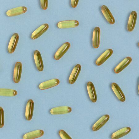Pattern made of omega 3 capsules on a blue background.
