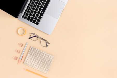 Layout of laptop, glasses and stationery on a beige background. E-learning concept with copy space.の写真素材