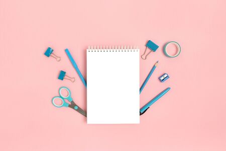 Blank notepad mockup with blue office supplies on a pink pastel background. Back to school concept.