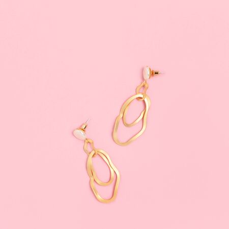 Golden earrings on a pink pastel background. Woman accessories layout.の写真素材