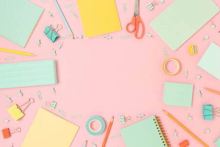 Border frame made of office supplies on a pink pastel background. Back to school concept with place...