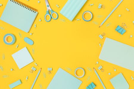 Border frame made of mint color school equipment on a bright yellow background. Creative concept...