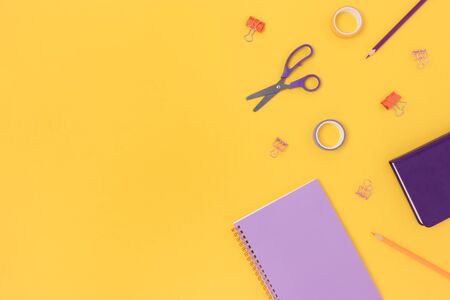 Border frame made of colorful office supplies on a yellow background. Creative concept with place...