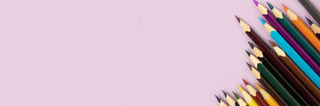 Top view of colorful pencils on a purple pastel background. Back to school concept with copy space.
