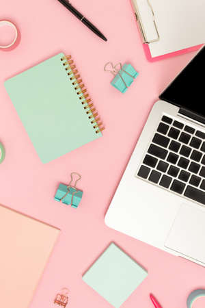 Top view of laptop and stationery on a pink pastel background. E-learning concept.