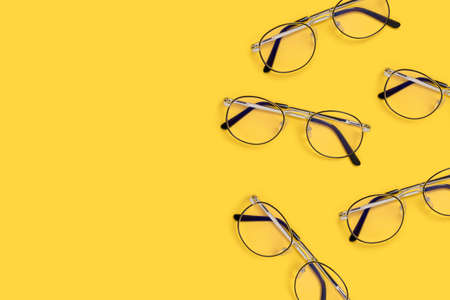Border frame made of eyeglasses on a yellow background. Accessories arrangement with place for text.の写真素材