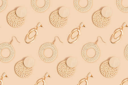 Different earrings pattern on a beige background. Monochrome fashion concept.