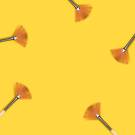 Border frame made of paint brushes on a yellow background. Place for your design.の写真素材