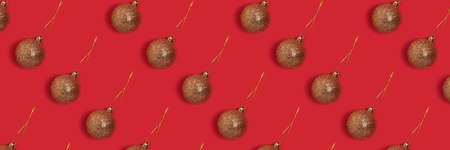 Banner with golden glittering Christmas baubles pattern on a red background. Festive composition.