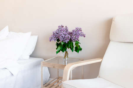 Bright room with bouquet of lilac on a glass tableの写真素材