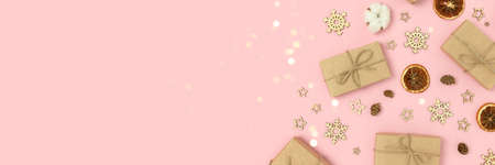 Frame made of natural Christmas decorations and gift boxes on a pink background. Festive banner with copy space.の写真素材