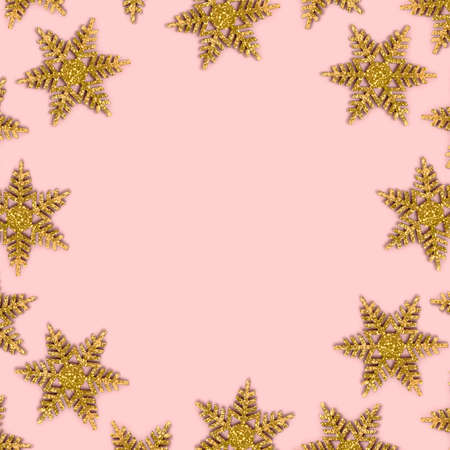 Frame made of golden snowflakes on a pink background. Christmas composition with copy space.の写真素材