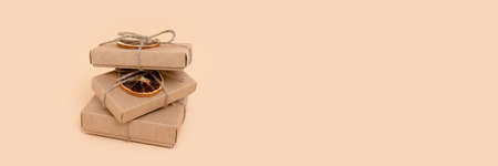 Banner with pile of gift boxes on a beige background. Holidays preparation concept with place for text.の写真素材