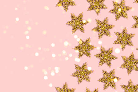 Frame made of golden snowflakes on a pink background. Christmas shiny composition with place for...