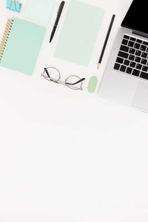Workspace with laptop, glasses and stationery. White flatlay with copy space.の写真素材