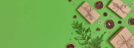 Banner with natural Christmas gifts, decorations and coniferous branches on a green background. Zero...