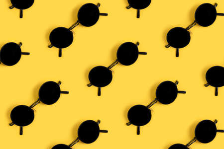 Pattern made of sunglasses on a yellow background. Creative summer concept.