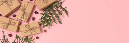 Banner with wrapped Christmas gifts and coniferous branches on a pink pastel background. Plastic free holidays concept with copy space.の写真素材