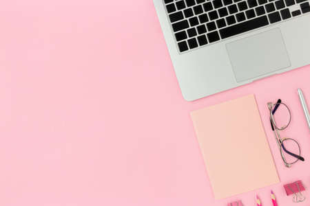 Top view of laptop, glasses, notepad and stationery on a pink pastel background. E-learning monochrome concept with place for text.の写真素材