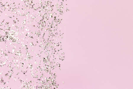 Silver glowing confetti scattered on a pastel purple background. Shiny composition with copy space.の写真素材