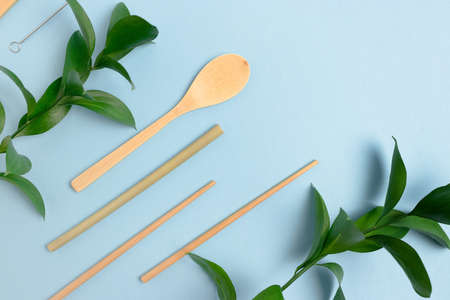 Frame made of bamboo cutlery and green leaves. Zero waste concept on blue pastel background.の写真素材