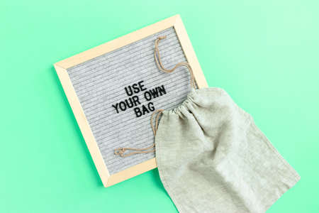 Canvas bag on mint background. Letterboard with quote Use your own bagの写真素材