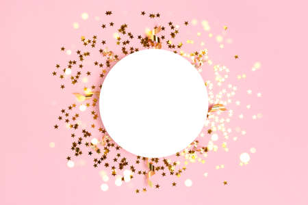 Round paper card mockup with frame made of gold stars confetti. Festive flatlay on a pink pastel background.の写真素材