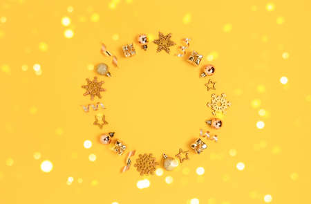 Wreath made of gold Christmas decorations and confetti. Monochrome festive frame on a yellow background.の写真素材