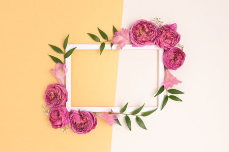 Flower border frame made of rose on a beige and gold background. Greeting card template with copyspace. Springtime holidays layout.の写真素材
